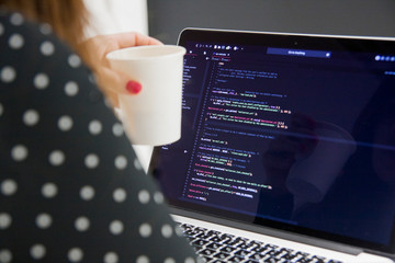 Wall Mural - woman programmer with cup of coffee working on laptop computer in office