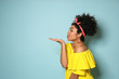 © Pixel-Shot - Portrait of young African-American woman blowing kiss on color background