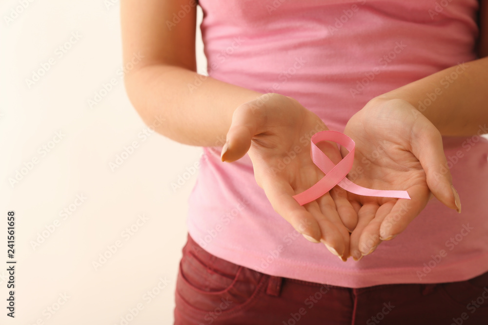 Woman with pink ribbon on light background. Breast cancer awareness concept
