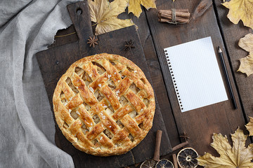 baked whole round apple pie on a brown wooden board, puff pastry