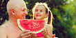 Smiling family with watermelon in the garden on the grass in summertime