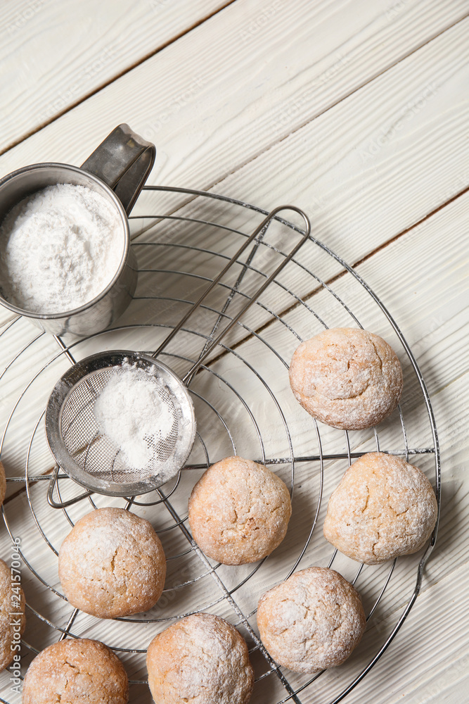 Cooling rack with tasty cookies and sugar powder on light table