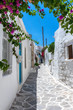 Kleine, weiße Gasse mit bunten Blumen und farbigen Türen auf den Kykladen im Sommer, Griechenland
