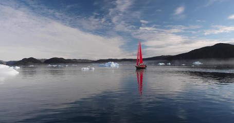 Wall Mural - little red sailboat cruising among floating icebergs in disko bay glacier during midnight sun season