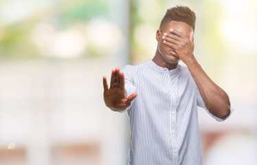 Poster - Young african american man over isolated background covering eyes with hands and doing stop gesture with sad and fear expression. Embarrassed and negative concept.