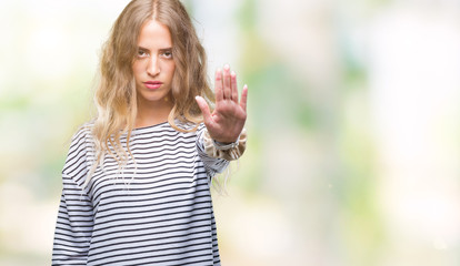 Wall Mural - Beautiful young blonde woman wearing stripes sweater over isolated background doing stop sing with palm of the hand. Warning expression with negative and serious gesture on the face.