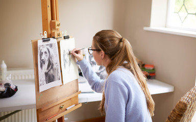 Wall Mural - Side View Of Female Teenage Artist Sitting At Easel Drawing Picture Of Dog From Photograph In Charcoal