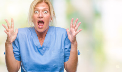 Sticker - Middle age blonde woman wearing doctor nurse uniform over isolated background crazy and mad shouting and yelling with aggressive expression and arms raised. Frustration concept.