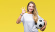 © Krakenimages.com - Young beautiful blonde woman holding soccer ball over isolated background doing ok sign with fingers, excellent symbol