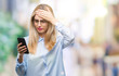 © Krakenimages.com - Young beautiful blonde business woman using smartphone over isolated background stressed with hand on head, shocked with shame and surprise face, angry and frustrated. Fear and upset for mistake.