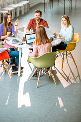 Team of a young coworkers dressed casually working together with laptops sitting at the round table in the office