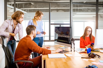 Team of a young programmers dressed casually working on computer code sitting in the modern office interior