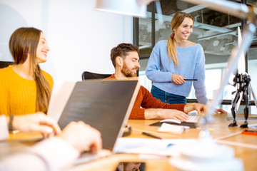 Team of a young programmers dressed casually working on computer code sitting in the modern office interior