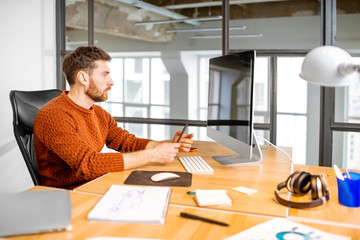 Portrait of a thoughtful man working with computer at the beautiful working place in the modern office interior