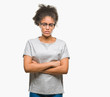 © Krakenimages.com - Young afro american woman wearing glasses over isolated background skeptic and nervous, disapproving expression on face with crossed arms. Negative person.