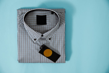 Poster - Top view of a business shirt on blue pastel background. The concept of fashion and sale of clothes for men, business and luxury shirts. Blue plaid shirt on the table.