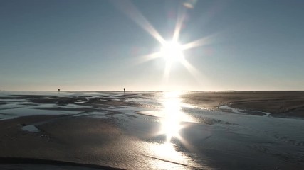 Wall Mural - Camera panning right on sun shining low on horizon at beautiful sandy beach with clear blue sky.