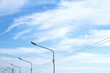 Part of electric poles and cable lines with stratocumulus clouds in blue sky background, perspective view with copy space