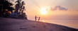 © olezzo - Beautiful young couple in love whirls holding hands on the beach at sunset during the honeymoon vacation travel