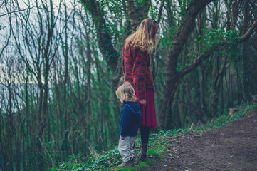 Young mother and toddler walking in the woods