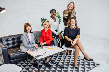 Portrait of young african confident business woman with her caucasian female business team looking at camera with happy expression isolated over white background