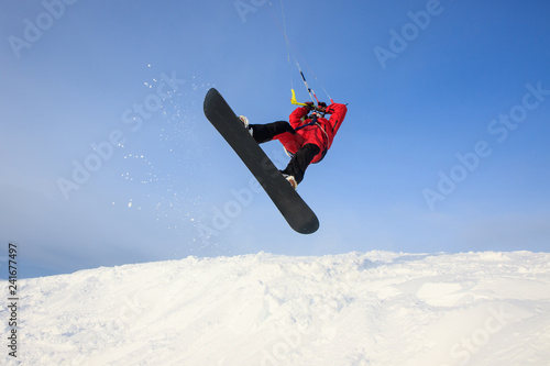 Professional kite boarding rider sportsman with kite in sky jumps high  acrobatics kiteboarding trick with grab of kiteboard. Recreational  activity, extreme active sports, snowkiting ski snowboard - Buy this stock  photo and