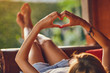 © astrosystem - Girl holding a heart-shape symbol while lying on the couch.