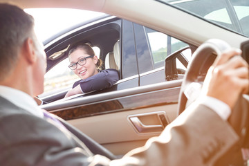 Smiling businesswoman talking to executive while sitting in car