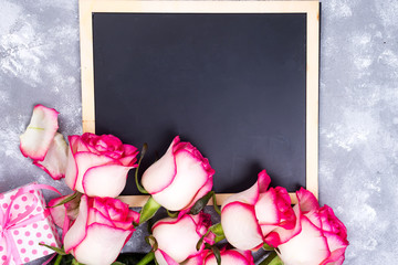 Canvas Print - Frame composition with roses and gift box on stone background. Flat lay, top view. Valentines day