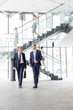 © moodboard - Businessmen talking while walking against staircase at new office
