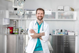 Fototapeta  - Portrait of smiling doctor standing with arms crossed at veterinary clinic