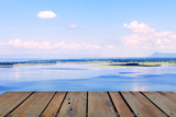 Fototapeta Natura - Old wood terrace with perspective view on blue lake and blue sky. Apply for poster, background, backdrop. There is copy free space fot texture.