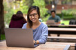 © elnariz - Chinese technology student on laptop at school on outdoor table with classmates