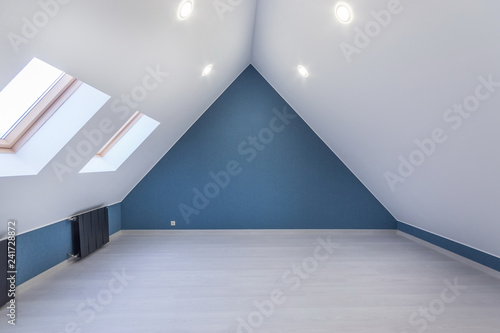 Empty Attic Room With Sloping Ceiling And Two Skylight Windows