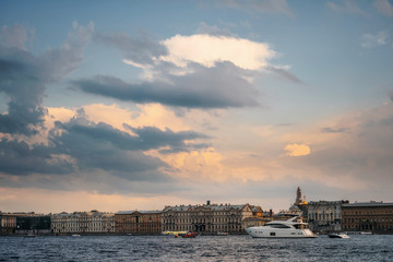 Tourist boats and yachts floats on Neva river on the background of typical architecture and Palace Embankment in the evening at golden sunset, Saint Petersburg, Russia