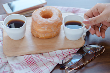 Wall Mural - Woman pick cup of coffee on table by sugar donuts