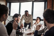© alfa27 - Multi ethnic people entrepreneurs meeting, small business concept. Afro american chief executive of big company presents new marketing strategy to coworkers gathering around a conference table.
