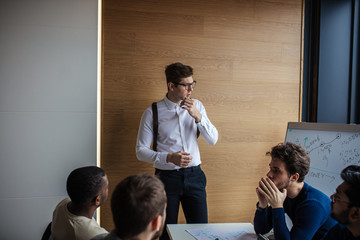 Canvas Print - African American male couch, dressed in formal suit leads brainstorming meeting in construction company office. Businessman in meeting with colleagues in conference room.