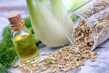 A Bottle Of Fennel Essential Oil With Fresh Green Fennel Twigs And Fennel Seeds In The Background