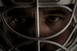 Detail of a male face in a goalie hockey mask.This is a detail hockey goalie. He is concentrated on game.