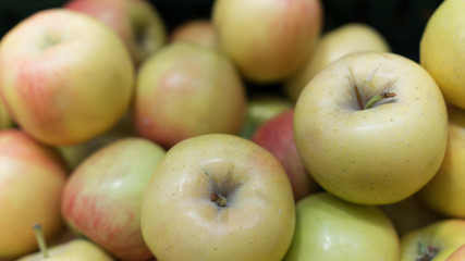 Closeup of many green yellow apples in wooden basket at market shop. Pattern of fresh apples in the market.