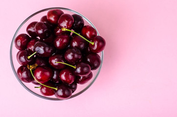 Wall Mural - Glass bowl with cherry on pink background