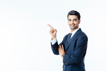 Portrait of a smiling, successful businessman in black suit and tie pointing up isolated on white background