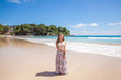 Girl wearing floral pink maxi skirt standing barefoot on the sea shore while sky is incredible blue, Thailand, Phuket