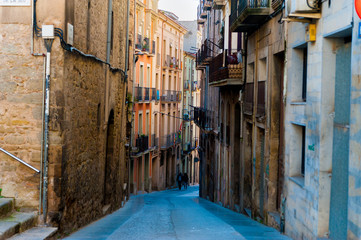 people walk in street of small catalan spanish medieval town during sunny spring day