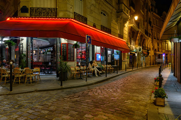 Wall Mural - Cozy street with tables of cafe in Paris at night, France