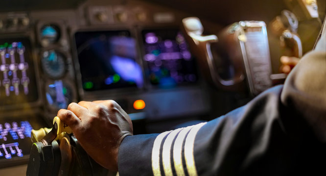 cropped hands of african pilot flying a commercial airplane
