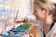 Frau beim Malen mit Pinsel vor Farbpalette