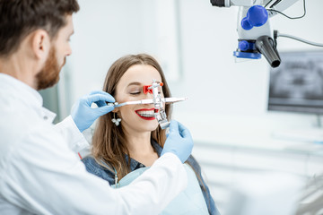 Wall Mural - Dentist putting jaw measurement system to a young woman patient in the dental office