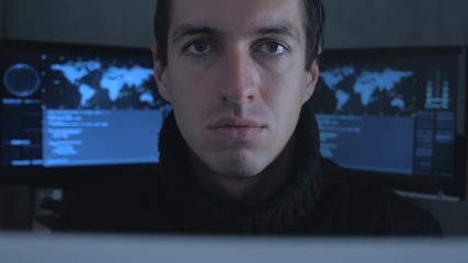 Close up Portrait of IT professional hacker programmer in cyber security center filled with display screens.